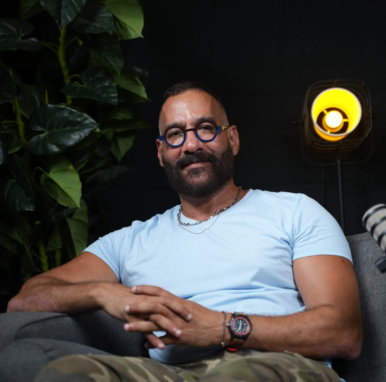 Invité souriant assis dans un studio de podcast sombre