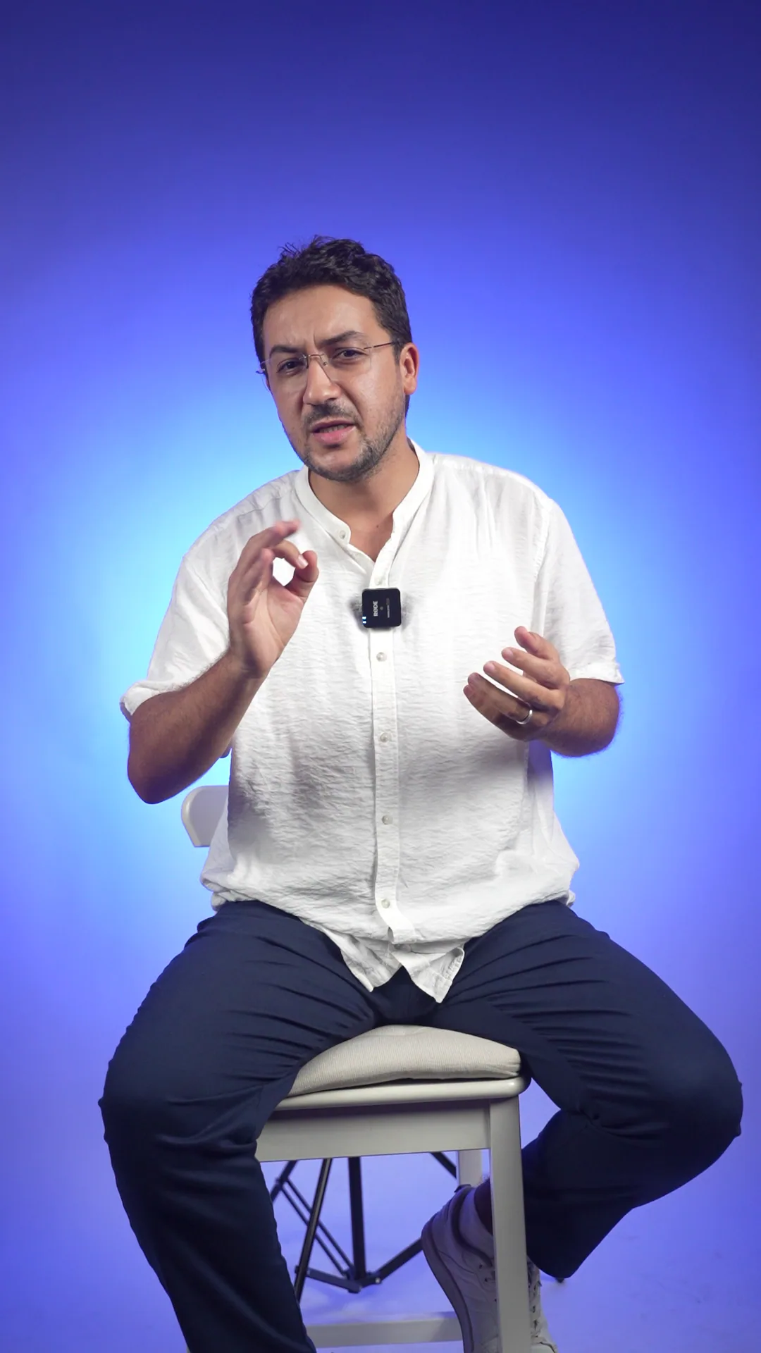 Intervenant sur un tabouret devant un fond de studio bleu